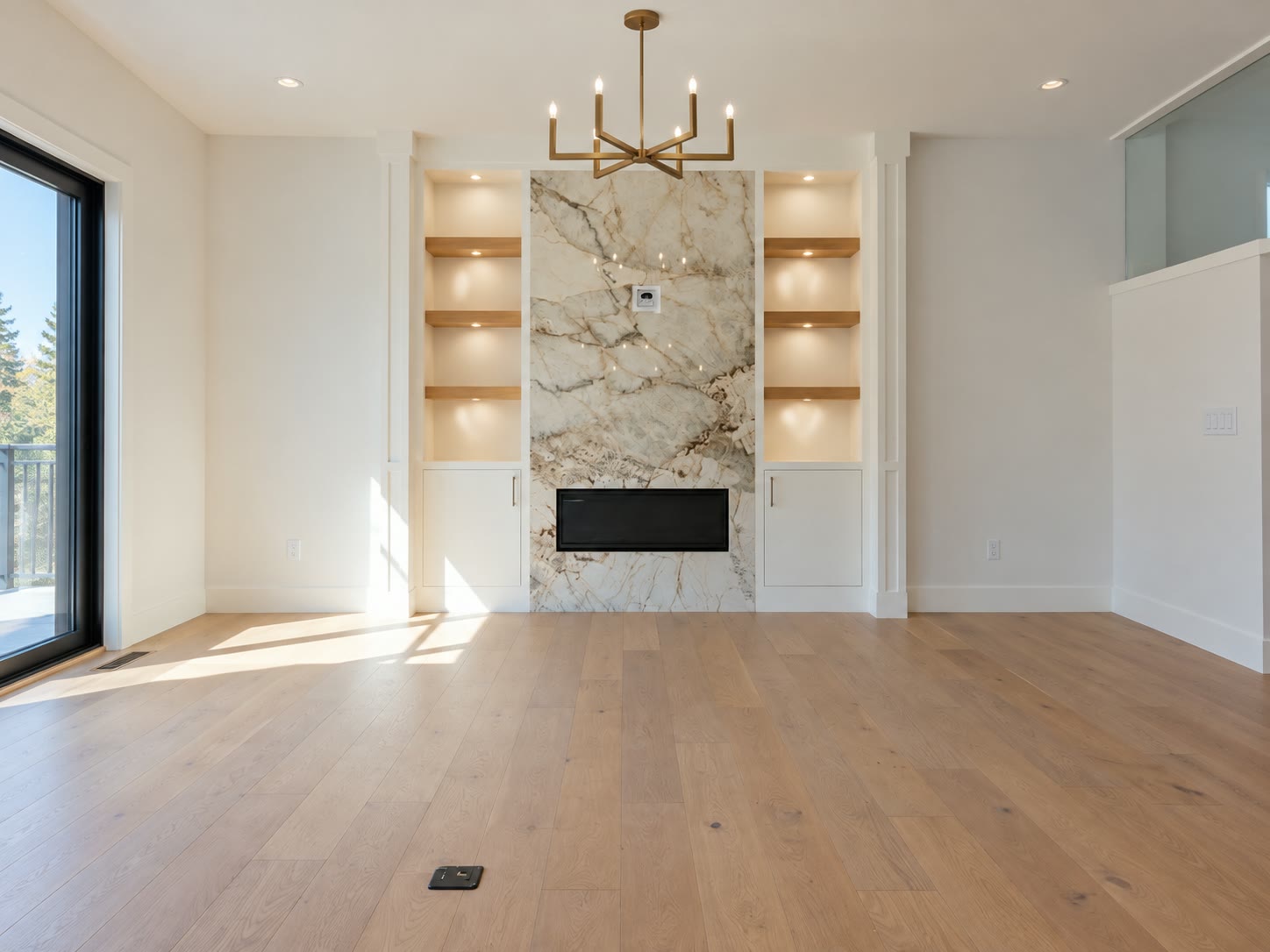 Great room in a Brar Homes build: a marble fireplace wall between lit oak built-ins, under a brass chandelier