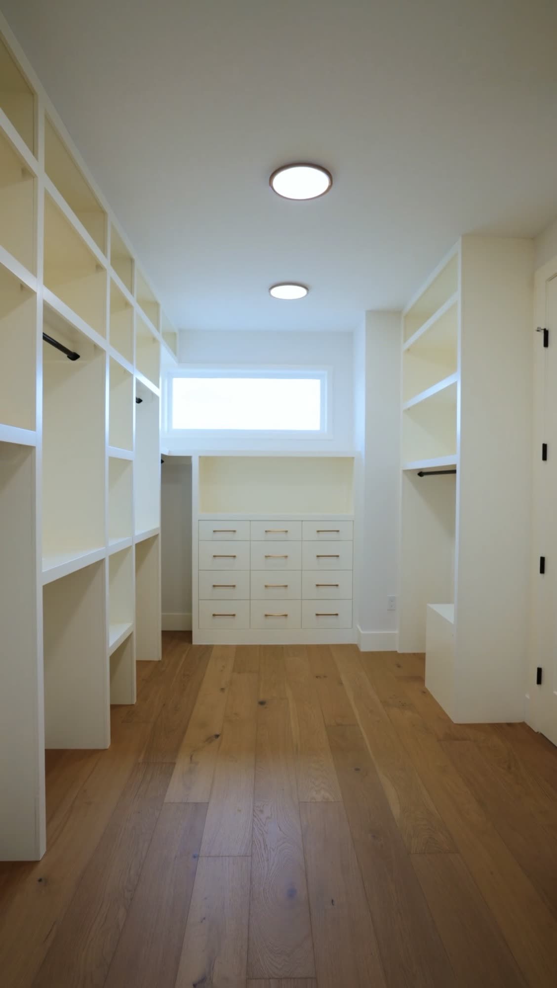 Walk in closet with open shelving down both walls and an oak floor
