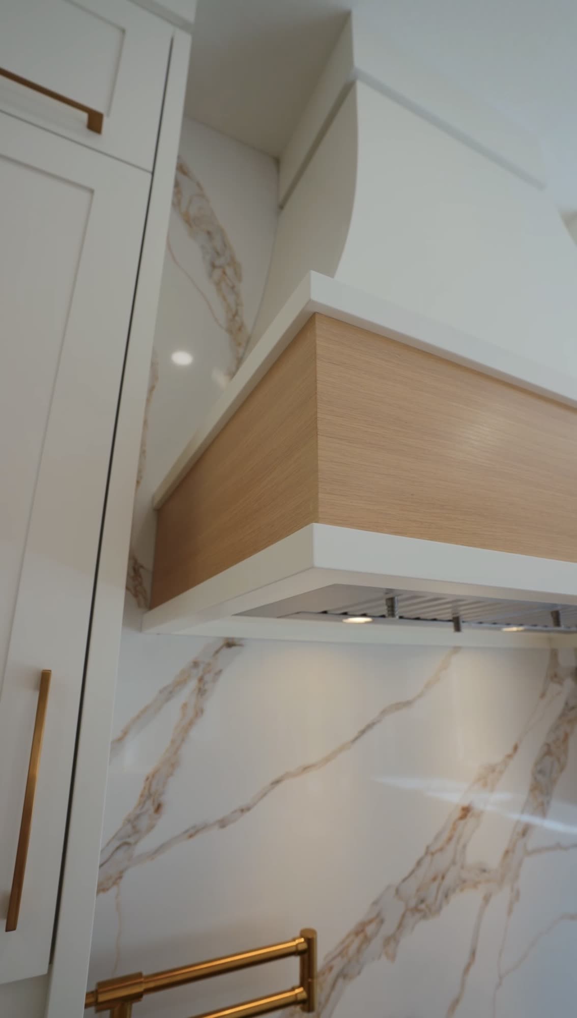 Oak banded range hood set against a marble slab
