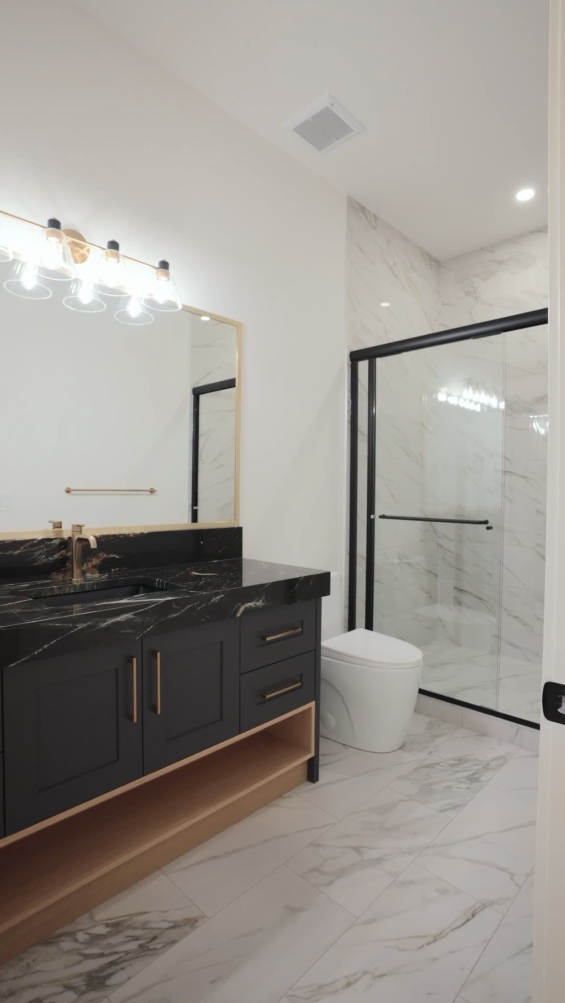 Bathroom with a black vanity, a marble surround and a glass shower