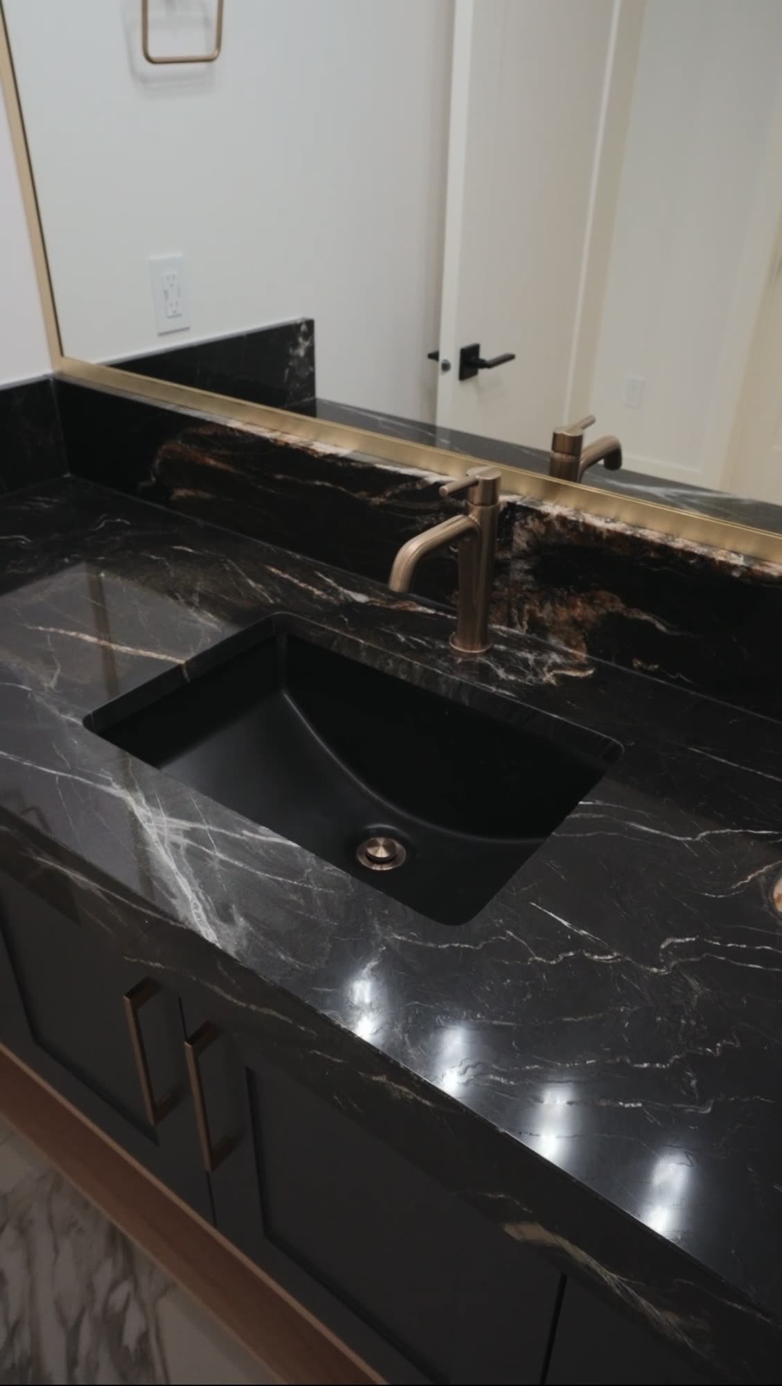 Undermount sink in a black granite counter with a brass tap
